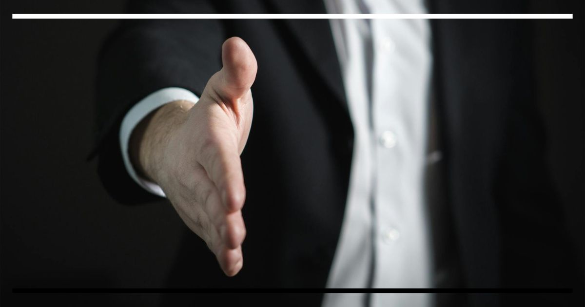 Mão estendida para cumprimento em traje social.