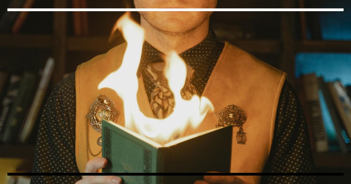 Livro verde em chamas nas mãos de uma pessoa, estante desfocada ao fundo.