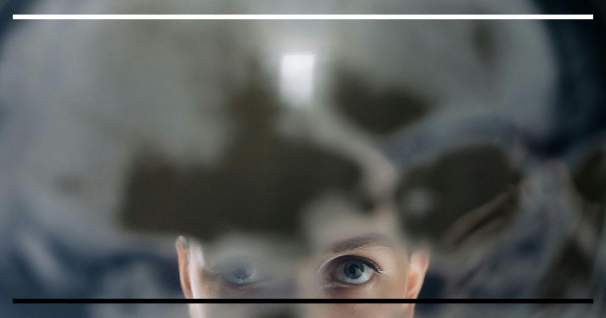 Olhos em foco vistos através de superfície translúcida com manchas orgânicas, sugerindo exame minucioso.