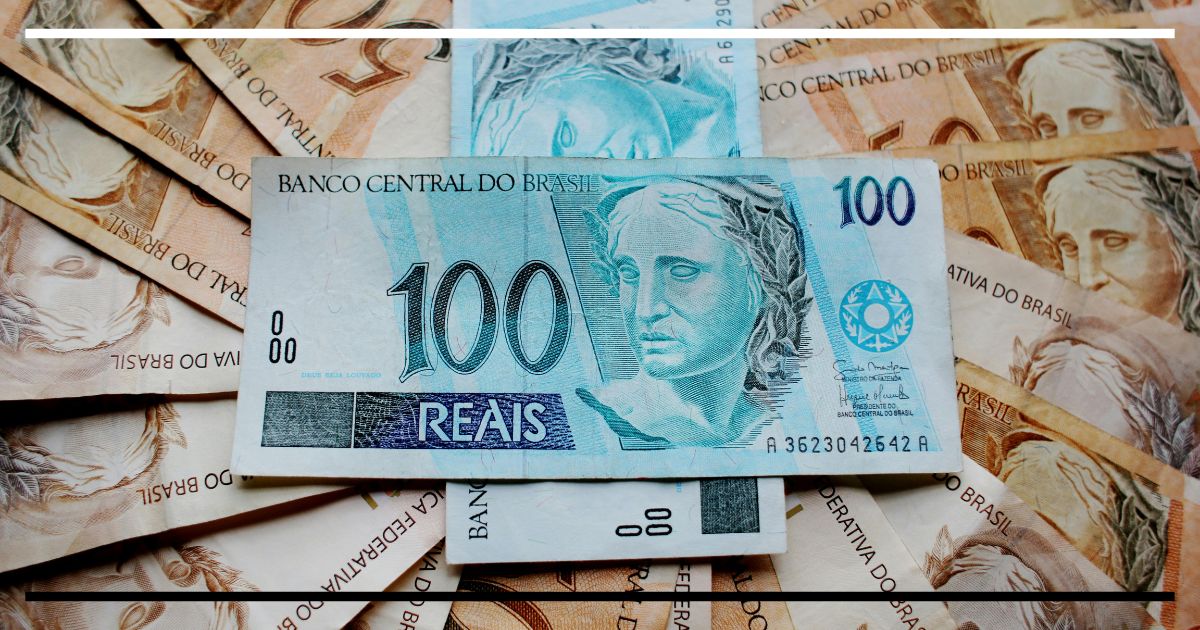 Cédulas de real em close, com nota de 100 em destaque sobre notas de 50, representando dinheiro em circulação.
