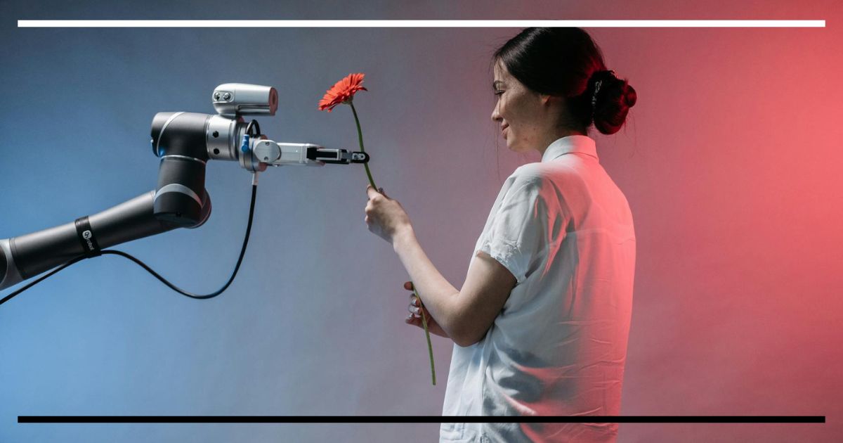 Mulher recebe de um braço robótico uma flor laranja em estúdio, luzes azul e vermelha ao fundo.
