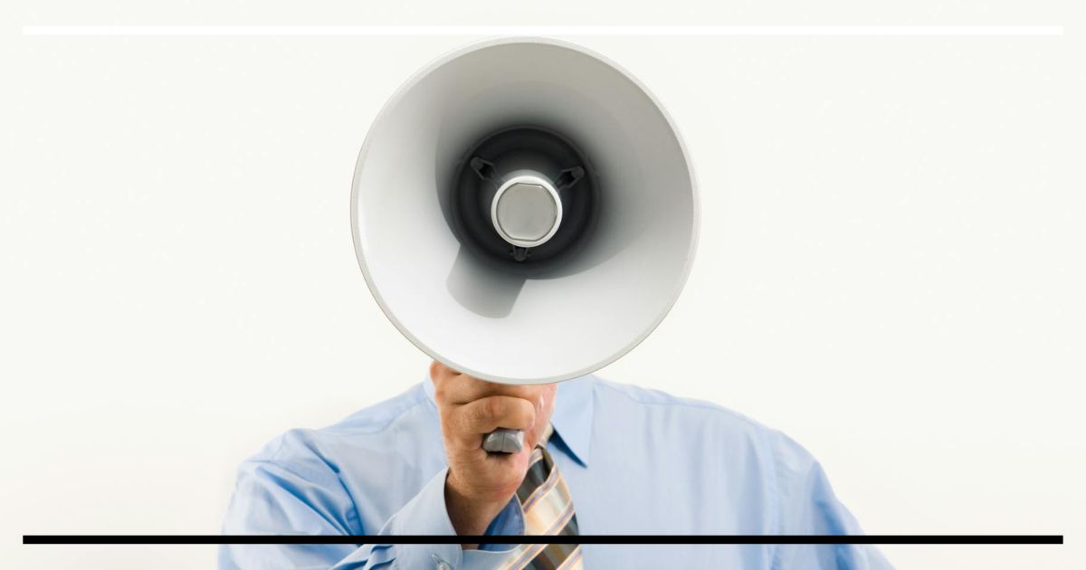 Pessoa segurando um megafone voltado para a câmera, representando excesso de fala.