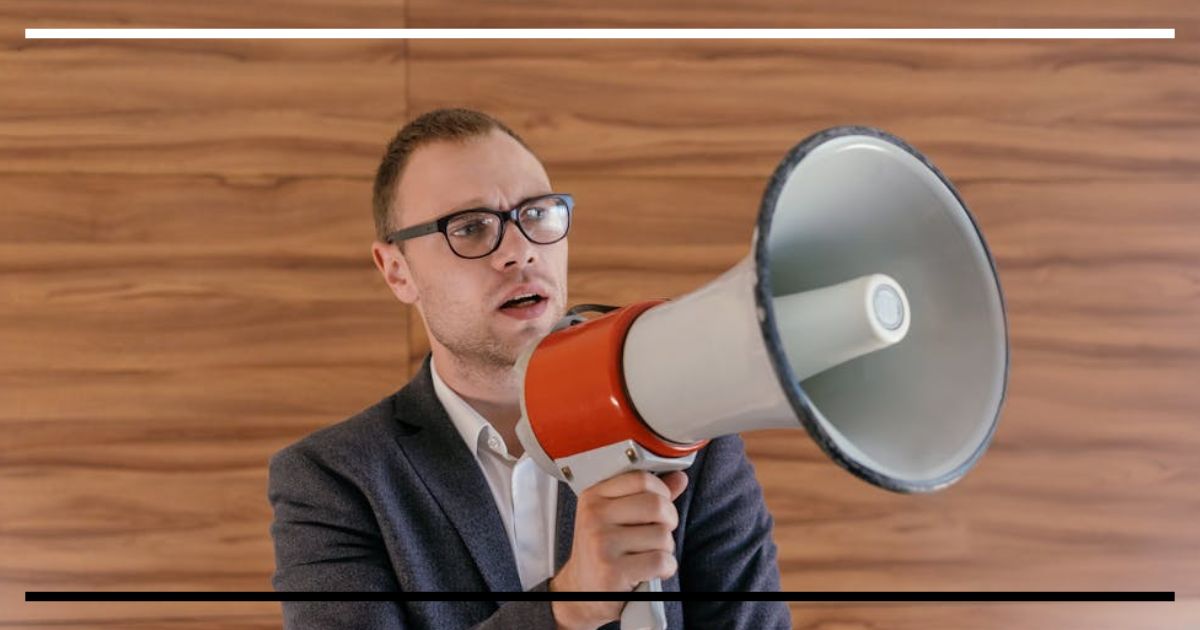 Homem de terno falando em um megafone.