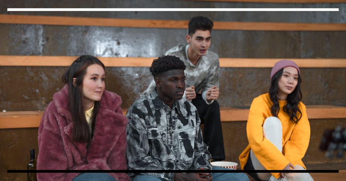 Jovens sentados observando uma cena sem intervir.