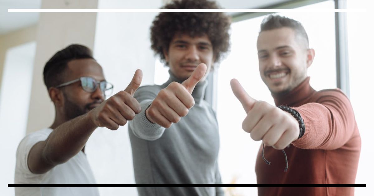 Três pessoas sorrindo e mostrando sinal de positivo.