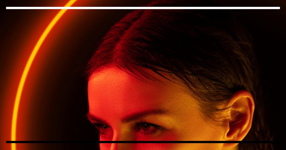 Mulher com iluminação circular laranja em volta da cabeça.