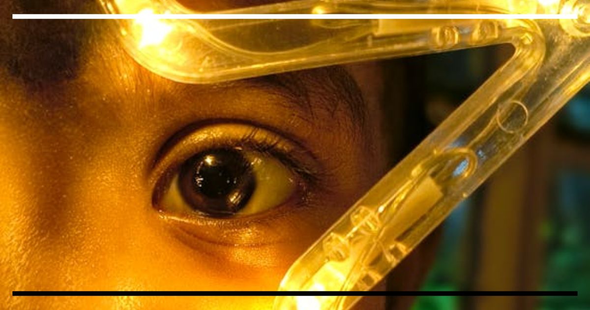 Olhar curioso de uma criança iluminado por luz amarela, simbolizando descoberta, atenção e a busca por respostas no aprendizado infantil.