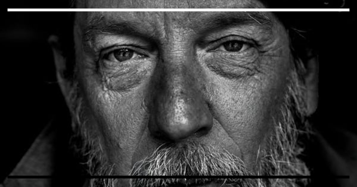 Close-up preto e branco de homem barbudo com olhar intenso, representando isolamento