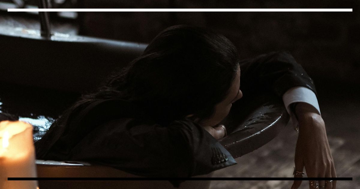 Pessoa em uma banheira antiga cercada por velas acesas, em ambiente escuro, simbolizando introspecção, tempo e beleza que se desfaz, inspiração estética de Frankenstein.