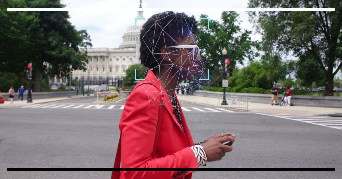 Mulher em frente ao Capitólio dos EUA com um overlay digital de grade e mira sobre o rosto, simbolizando a vigilância por reconhecimento facial e o viés algorítmico.