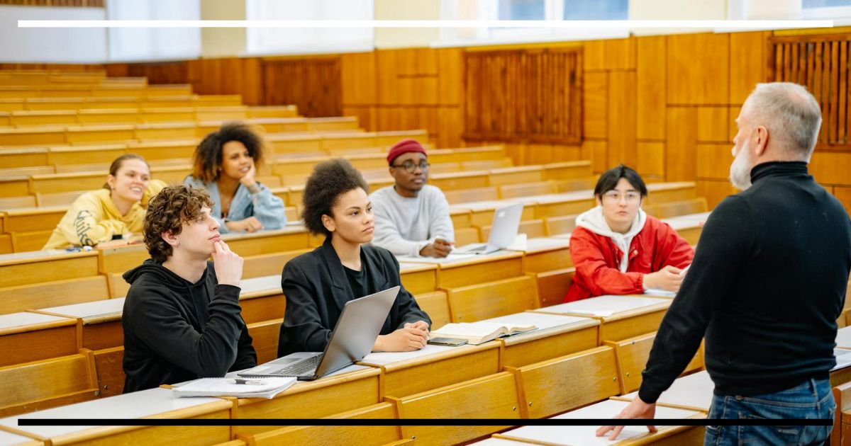 Professor dialogando com estudantes em sala de aula universitária