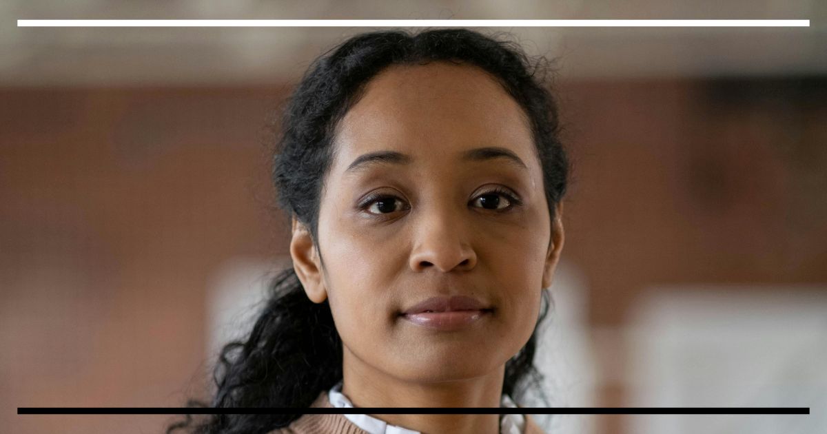 Professora em ambiente escolar refletindo sobre o sentido do ensino e da aprendizagem.