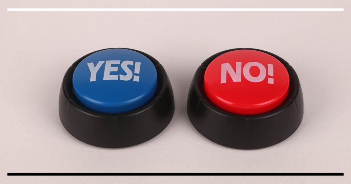 Dois botões de resposta sobre uma mesa: um azul com “YES!” e outro vermelho com “NO!”.