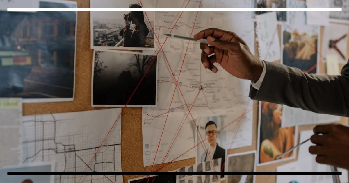 Mural com mapa, fotos e fios vermelhos conectando pontos, enquanto uma mão aponta para o quadro.