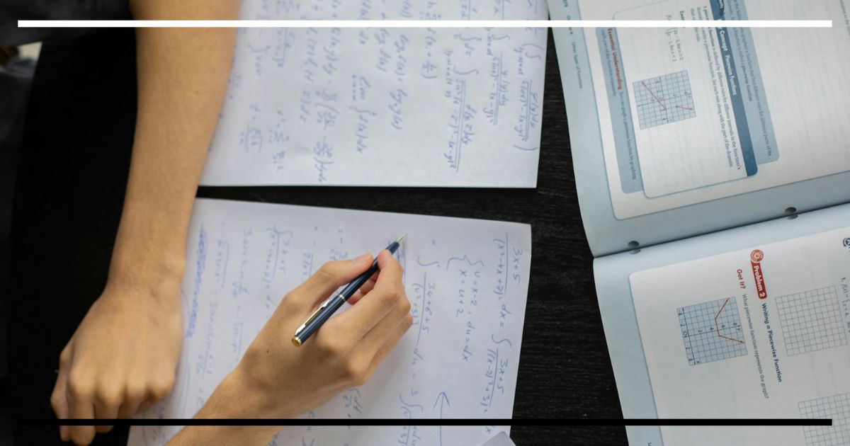 Mão escrevendo anotações densas em caderno ao lado de material de estudo, ilustrando o efeito geração no aprendizado.